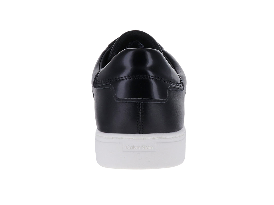 Tenis Calvin Klein color negro con suela blanca y correa ancha en la parte superior.