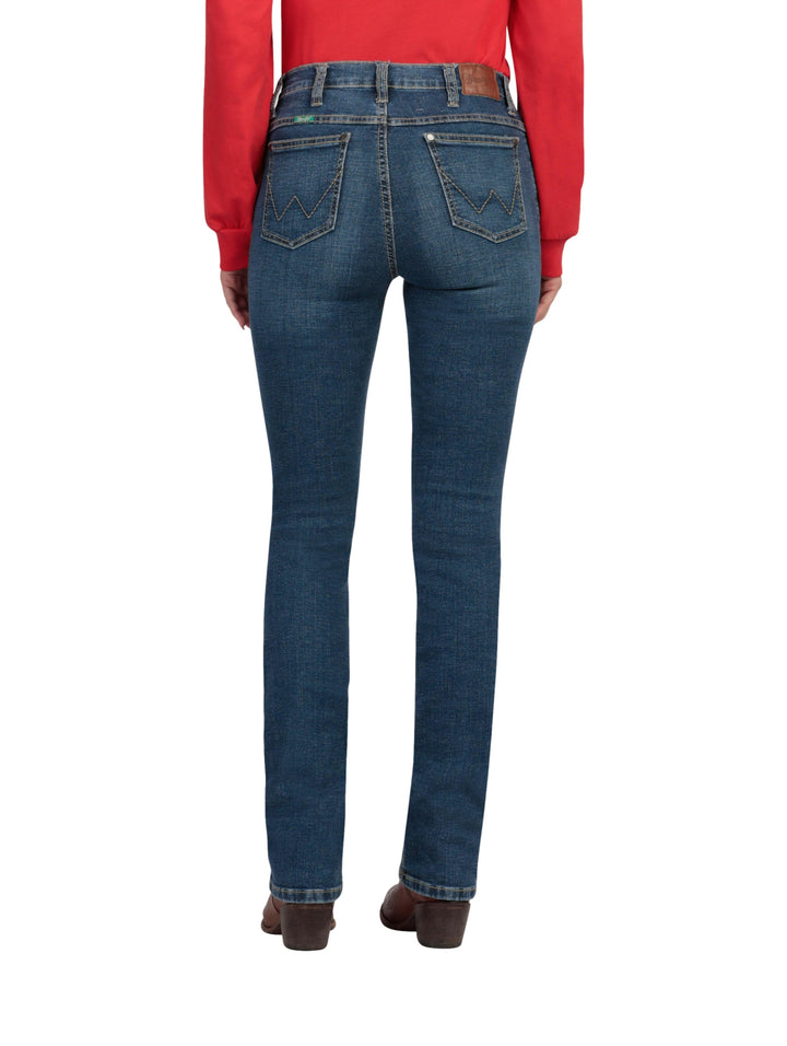 Mujer vistiendo jeans Wrangler de color índigo claro y corte recto con botas cafés.