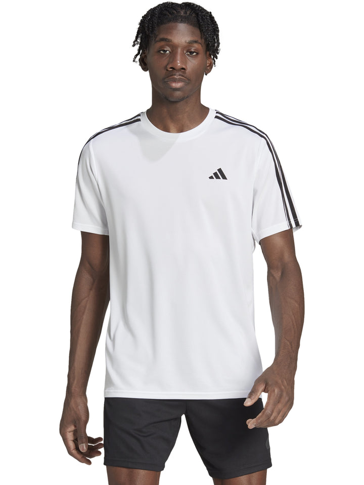 Hombre vistiendo camiseta Adidas blanca con tres franjas negras en los hombros y logo negro en el pecho.