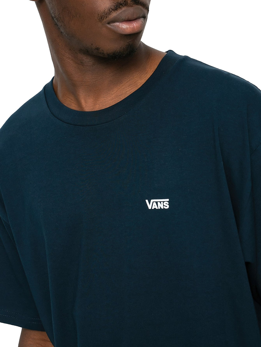 Hombre vistiendo una camiseta de manga corta color azul marino con un pequeño logotipo blanco de Vans en el pecho.