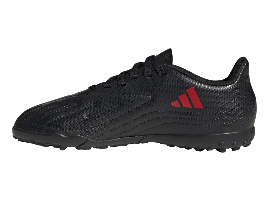 Calzado de fútbol Adidas negro con franjas rojas y suela para césped sintético.
