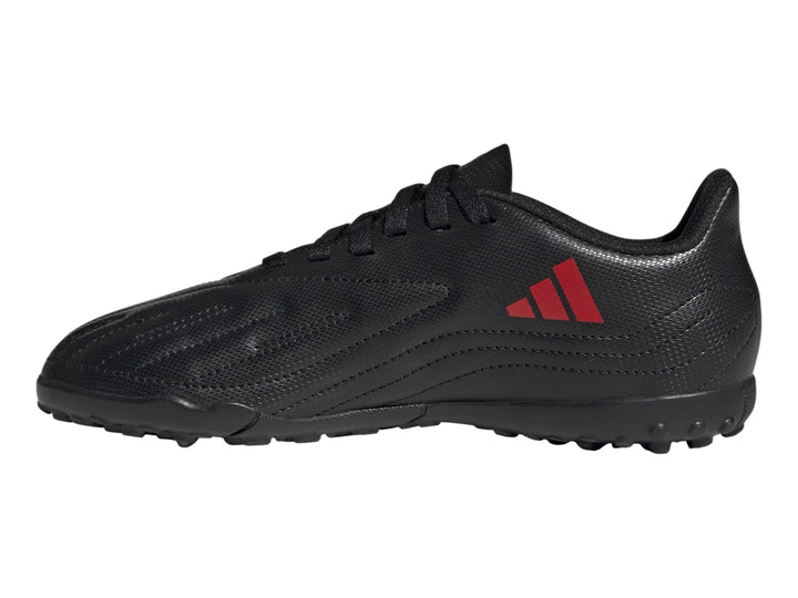 Calzado de fútbol Adidas negro con franjas rojas y suela para césped sintético.