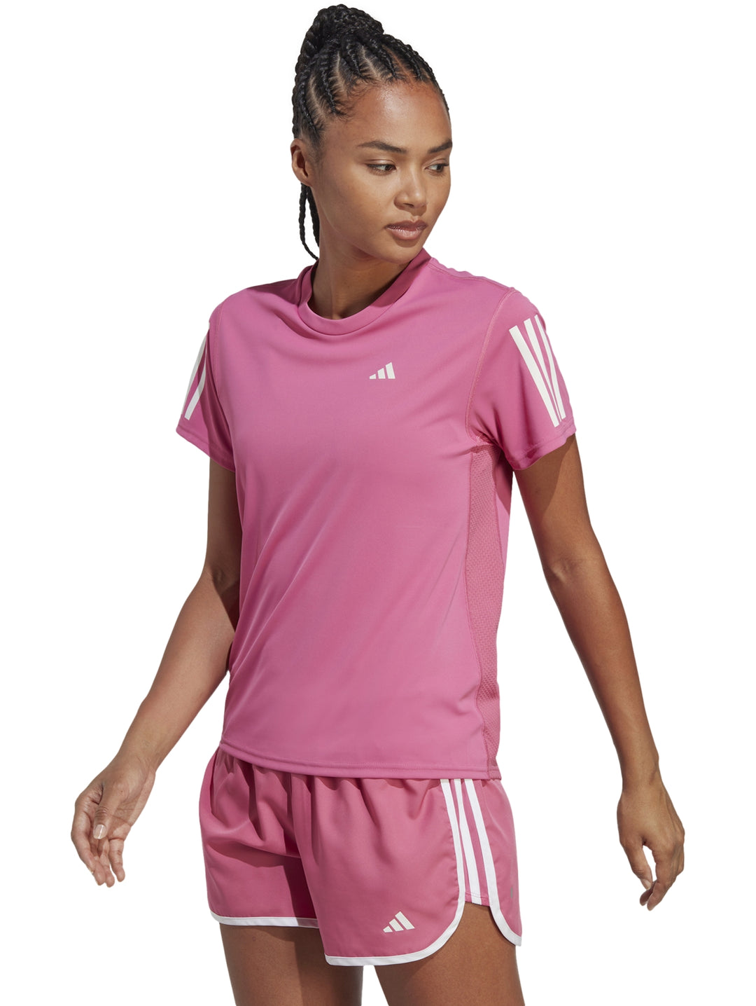 Mujer vistiendo camiseta deportiva Adidas color rosa con franjas blancas en las mangas.