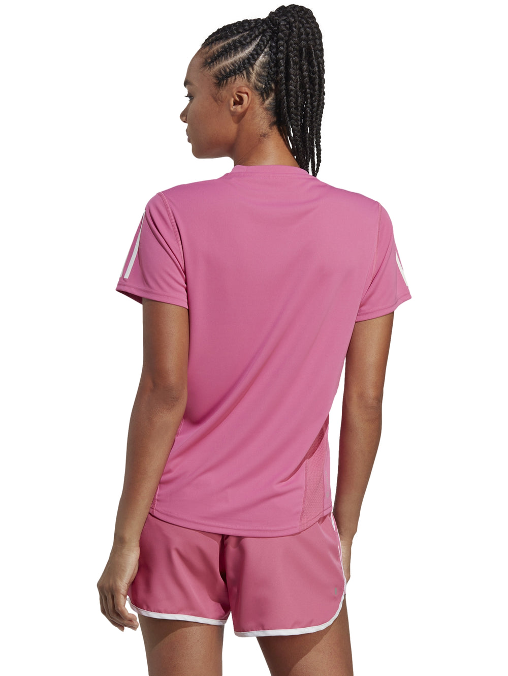 Mujer vistiendo camiseta deportiva Adidas color rosa con franjas blancas en las mangas.