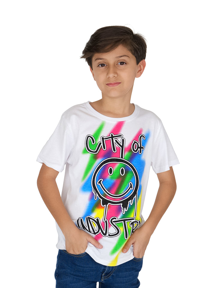 Niño con camiseta blanca de manga corta con estampado multicolor de carita feliz y texto.