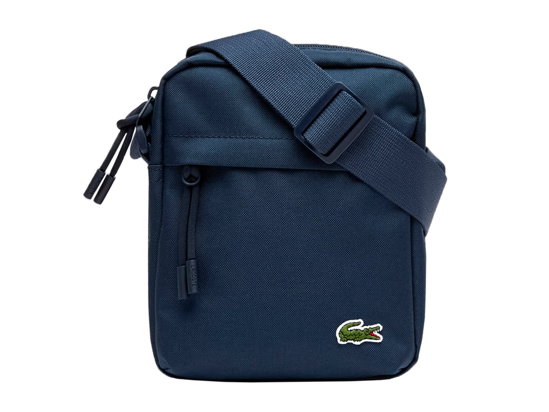 Bolso bandolera Lacoste color azul marino con correa ajustable y logotipo del cocodrilo en la parte inferior.