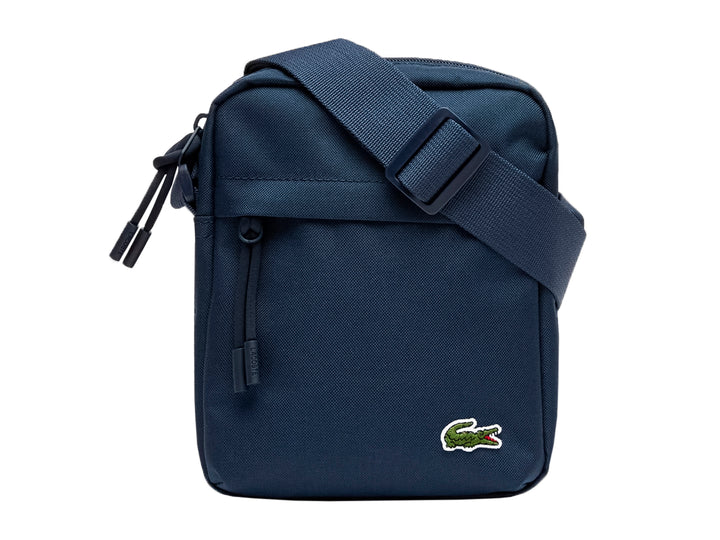 Bolso bandolera Lacoste color azul marino con correa ajustable y logotipo del cocodrilo en la parte inferior.