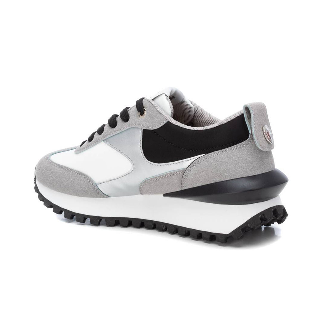 Tenis deportivos XTI en colores gris, blanco y negro con suela dentada.