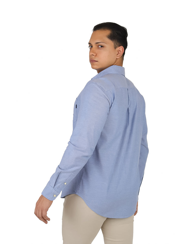 Hombre vistiendo una camisa Oxford de color azul claro con botones y manga larga.