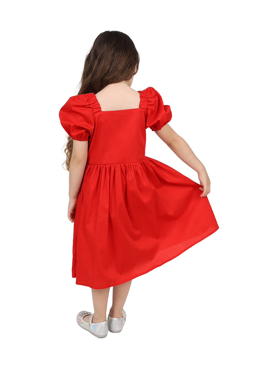 Niña vistiendo un vestido rojo de popelina con botones frontales y un detalle de corazón blanco.