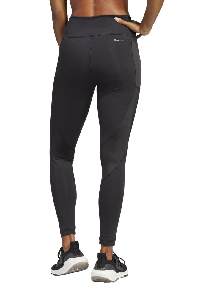 Mujer vistiendo leggings deportivos negros de talle alto marca Adidas.