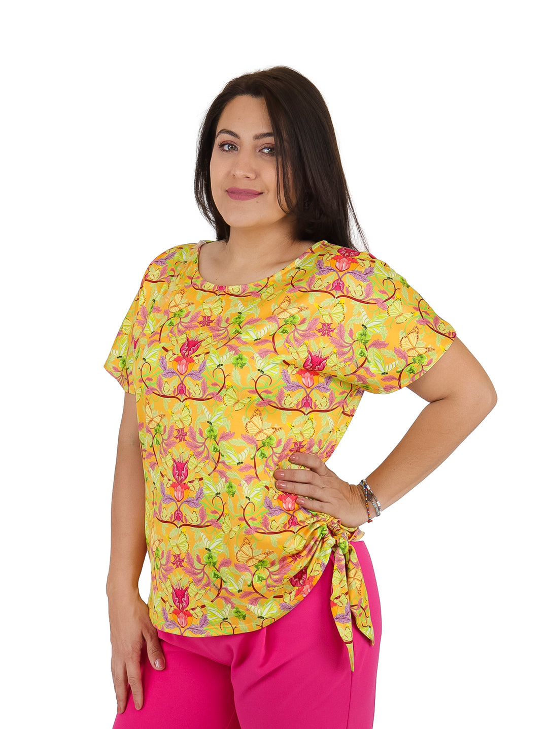 Mujer vistiendo blusa color mostaza con estampado floral de manga corta y detalle de nudo lateral.