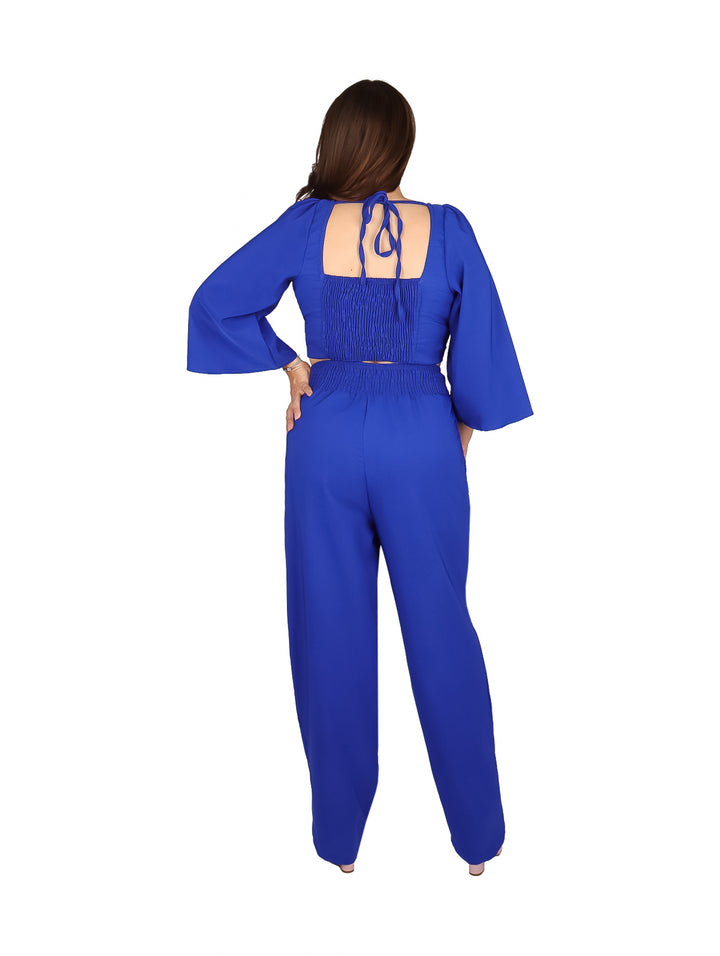 Mujer vistiendo conjunto de dos piezas color azul rey con pantalón ancho y blusa de mangas acampanadas.