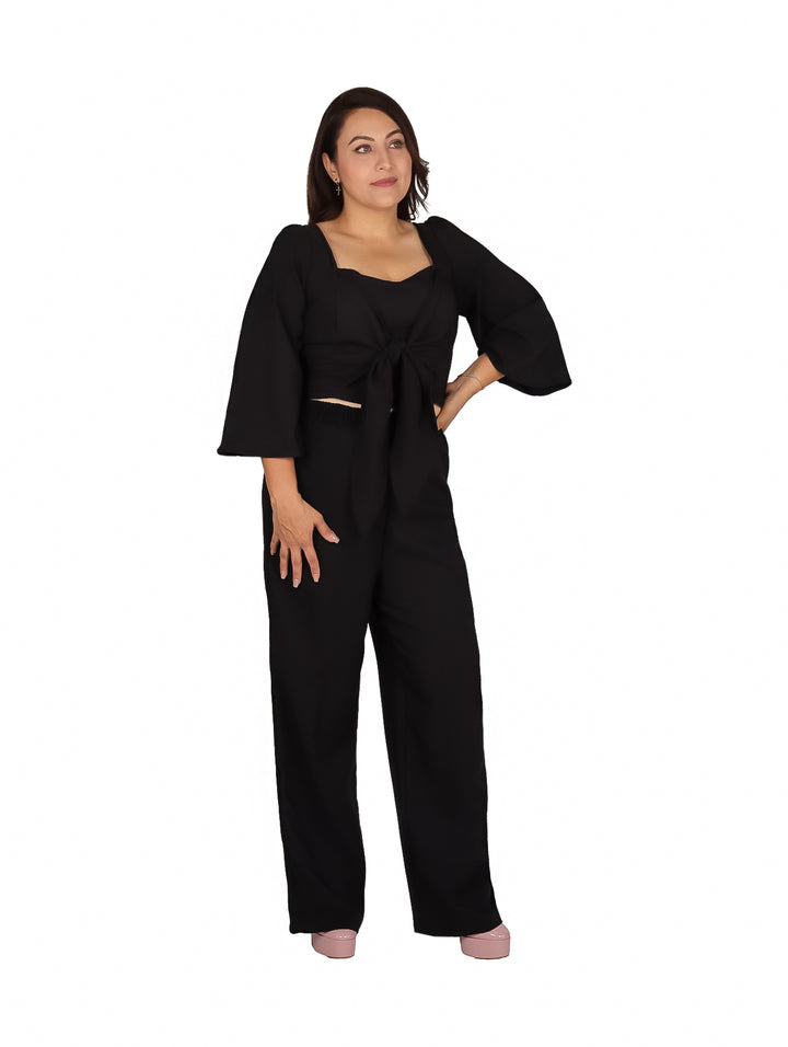 Mujer vistiendo un conjunto negro de dos piezas con pantalón ancho y blusa con nudo frontal.