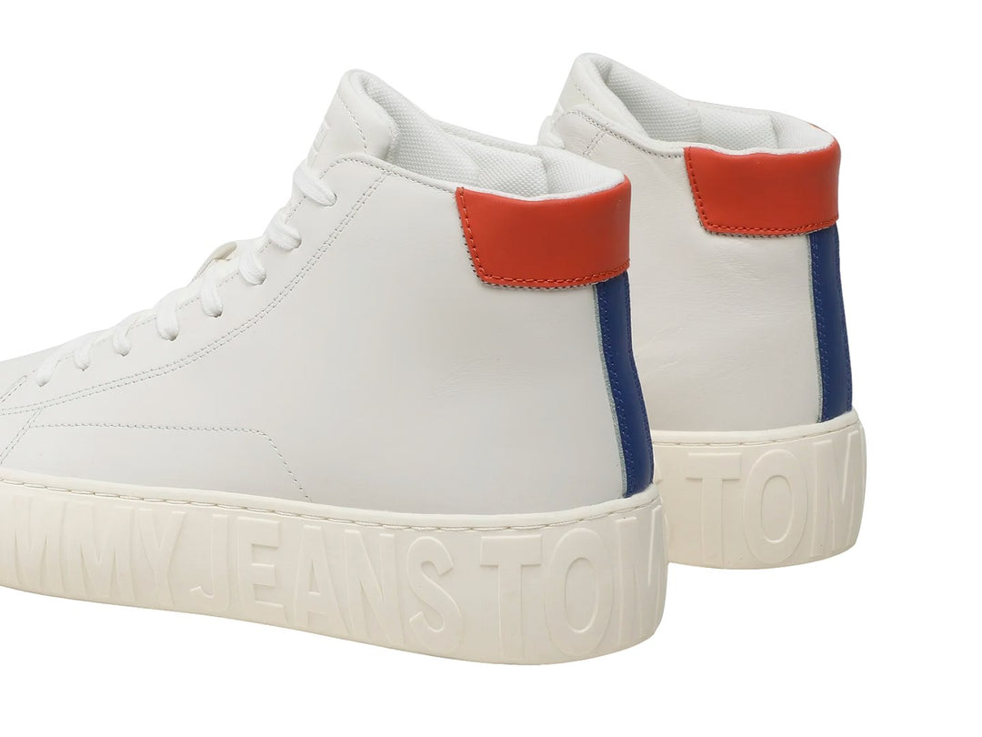 Tenis blancos de corte medio con suela gruesa y detalle rojo en el talón.