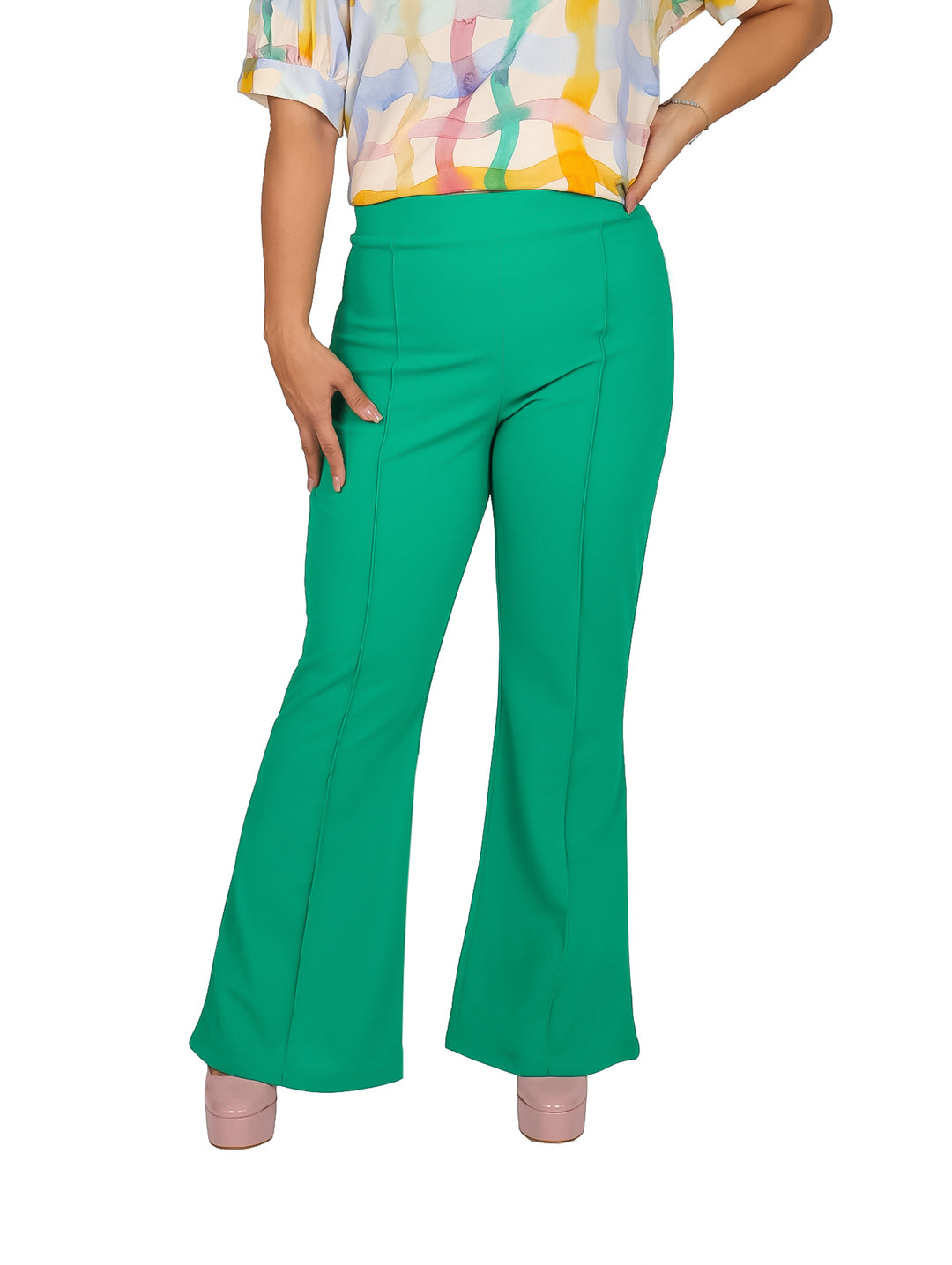 Mujer vistiendo pantalón campana color verde kelly y zapatos de plataforma rosa.