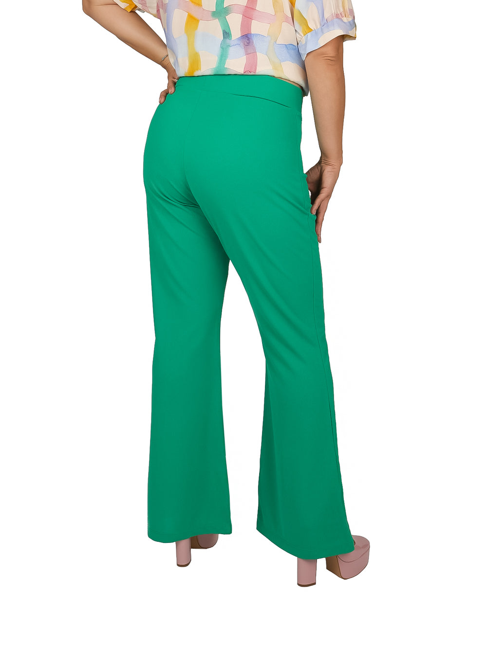 Mujer vistiendo pantalón campana color verde kelly y zapatos de plataforma rosa.