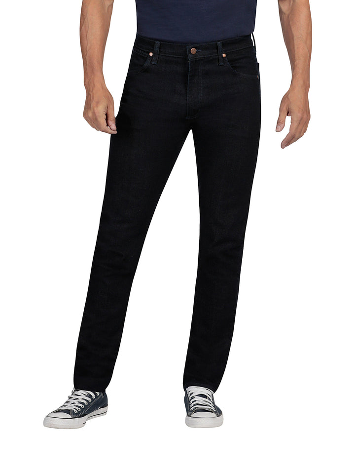 Hombre vistiendo pantalones Wrangler Stone Jeans Slim Fit en color negro y tenis azules.