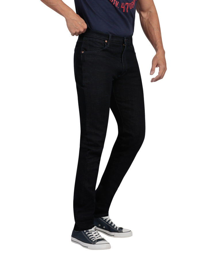 Hombre vistiendo pantalones Wrangler Stone Jeans Slim Fit en color negro y tenis azules.