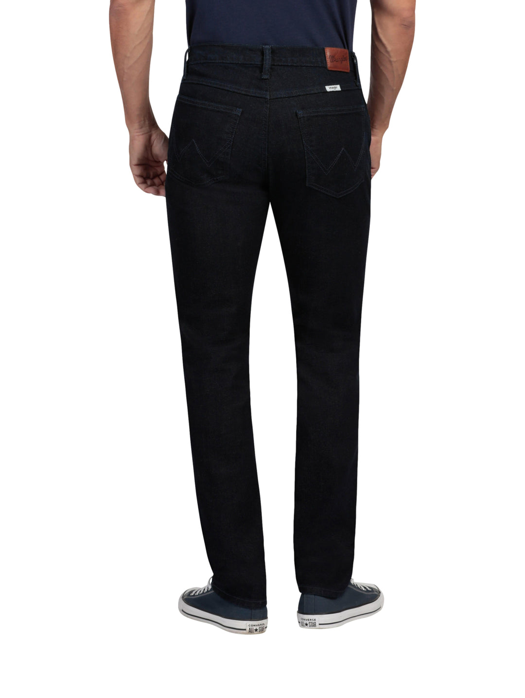 Hombre vistiendo pantalones Wrangler Stone Jeans Slim Fit en color negro y tenis azules.