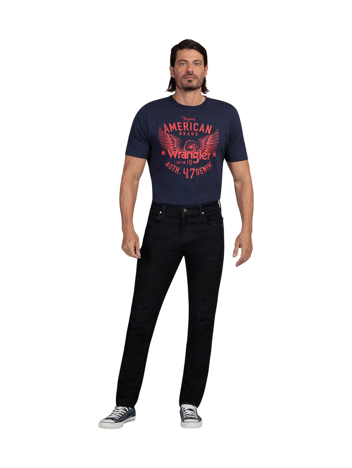 Hombre vistiendo pantalones Wrangler Stone Jeans Slim Fit en color negro y tenis azules.