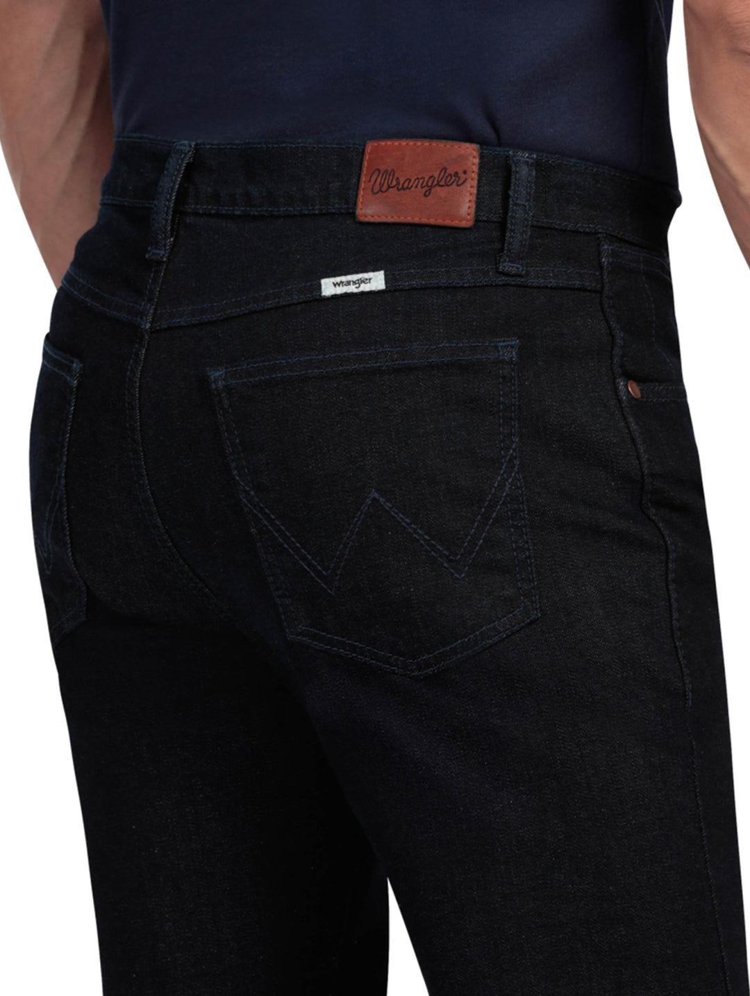 Hombre vistiendo pantalones Wrangler Stone Jeans Slim Fit en color negro y tenis azules.