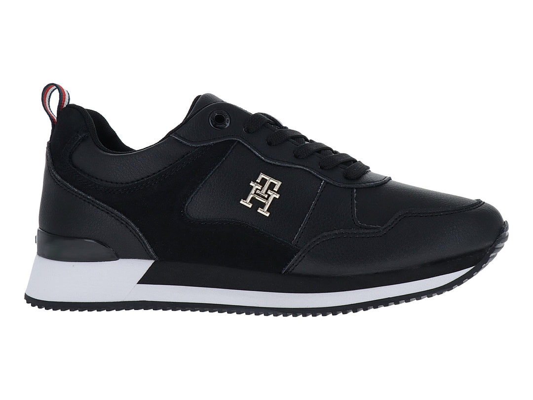 Tenis Tommy Hilfiger modelo Essential Runner en color negro con suela blanca y logo dorado lateral.
