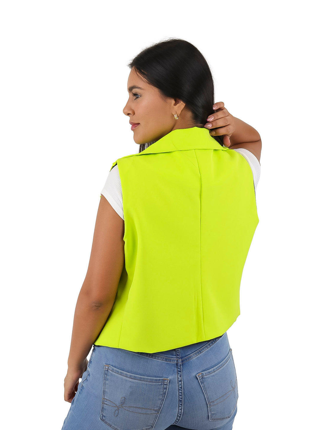 Mujer vistiendo un chaleco color lima brillante sobre una blusa blanca y jeans azules.