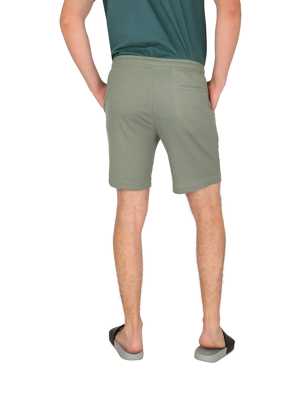 Hombre usando shorts de surf color olivo con cordón blanco.