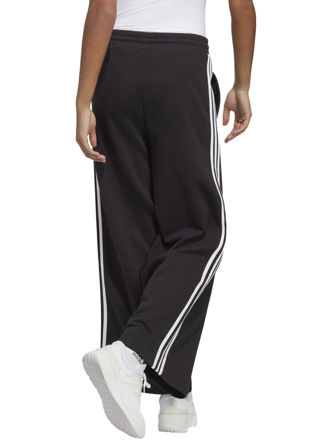 Pantalones deportivos Adidas de pierna ancha en color negro con tres franjas blancas laterales.