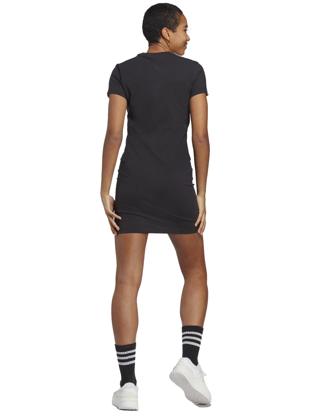 Mujer vistiendo un vestido deportivo corto de color negro con logo de Adidas en el pecho.