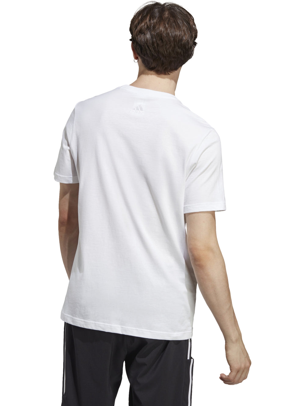 Hombre vistiendo playera blanca de manga corta con logotipo de Adidas en negro y pantalones deportivos negros.