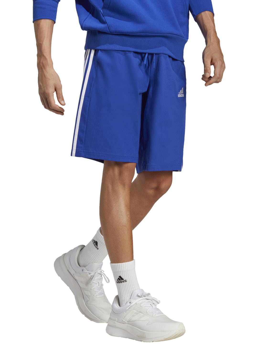 Hombre vistiendo shorts deportivos Adidas color azul con tres franjas blancas laterales.