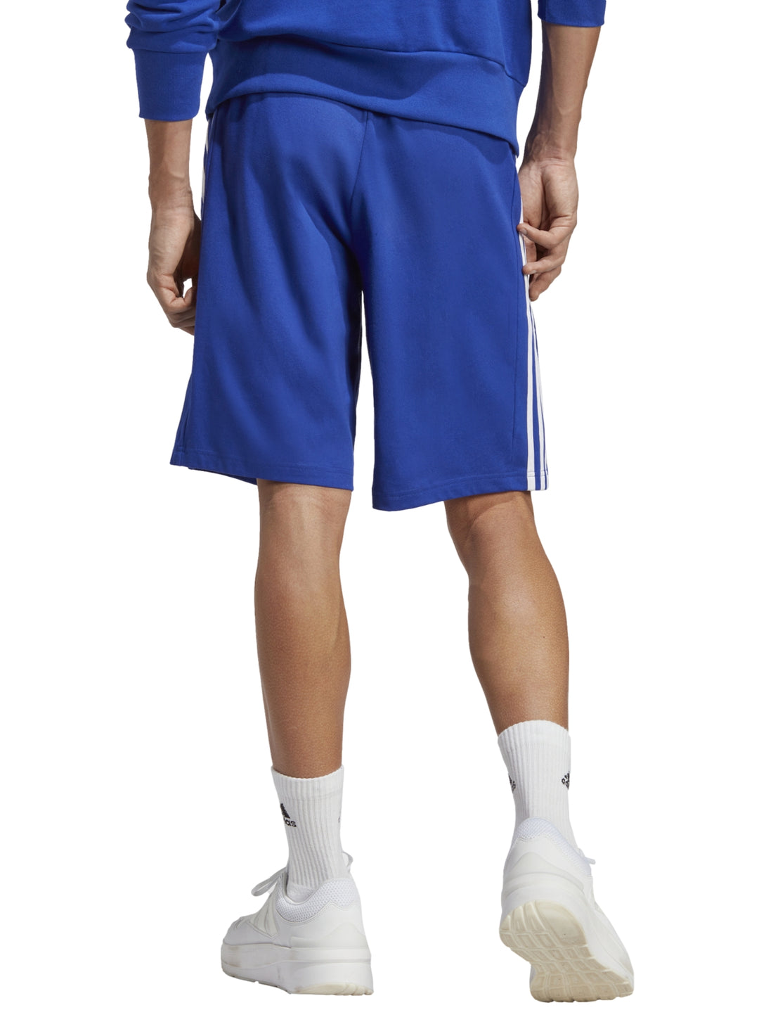Hombre vistiendo shorts deportivos Adidas color azul con tres franjas blancas laterales.