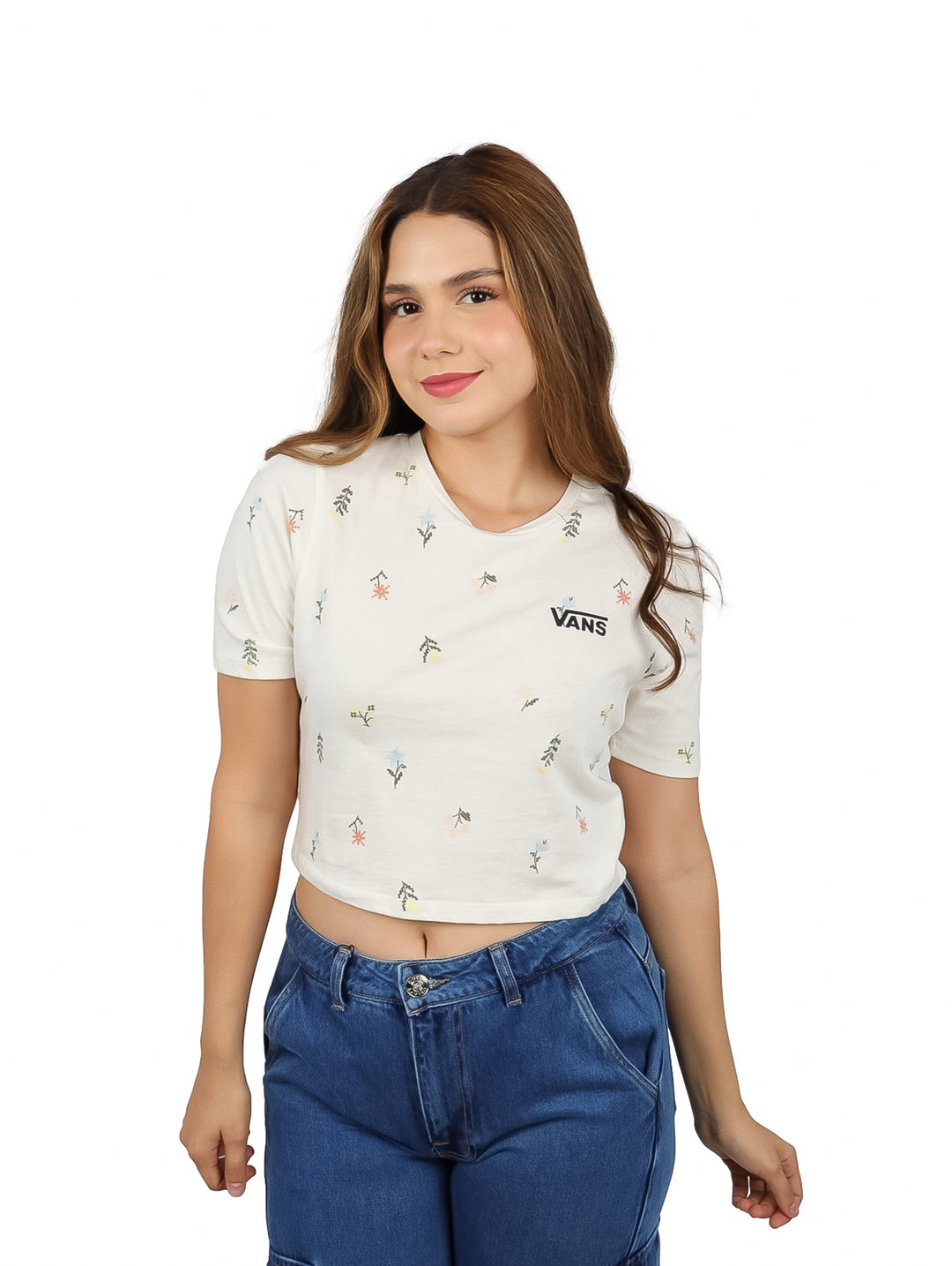 Mujer vistiendo camiseta crop blanca de VANS con estampado floral y pantalones vaqueros.