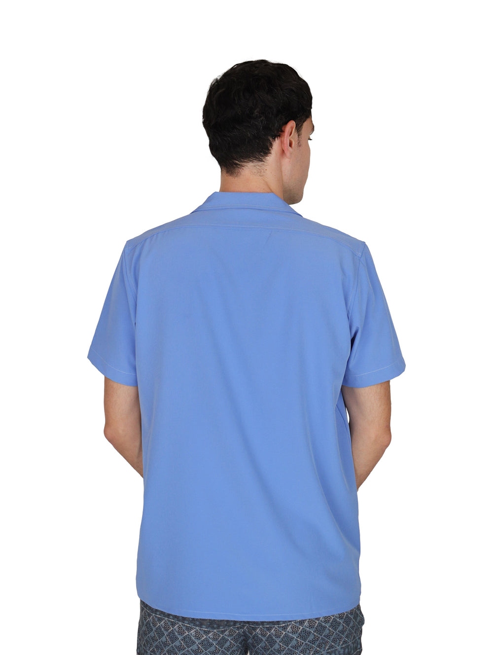 Hombre vistiendo una camisa casual de manga corta en color azul con cuello abierto y un bolsillo en el pecho.