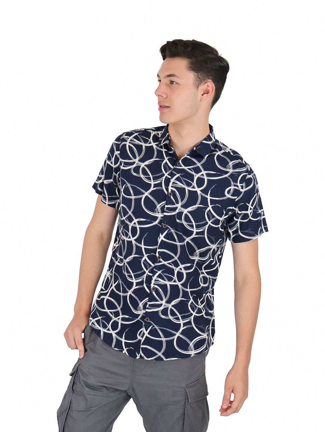 Hombre vistiendo camisa de manga corta azul marino con estampado de círculos blancos y pantalones grises.