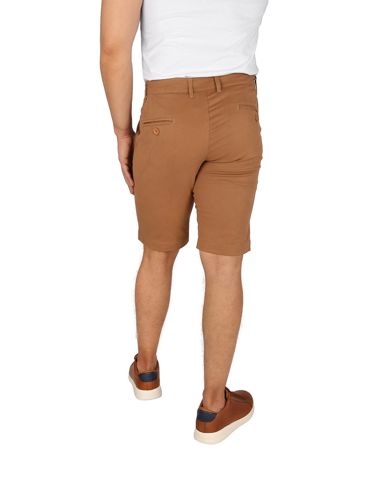 Hombre vistiendo bermudas de color beige estilo casual con calzado marrón sobre fondo blanco.