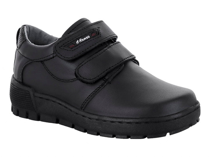 Zapato infantil color negro con cierre de velcro y suela gruesa.