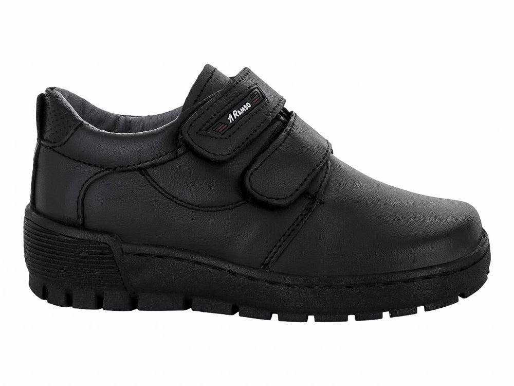 Zapato infantil color negro de material sintético con cierre de velcro y suela gruesa.