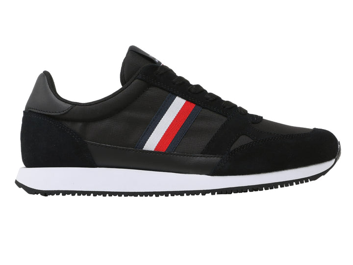 Tenis Tommy Hilfiger negros con suela blanca y detalle de franja roja, blanca y azul en el costado.