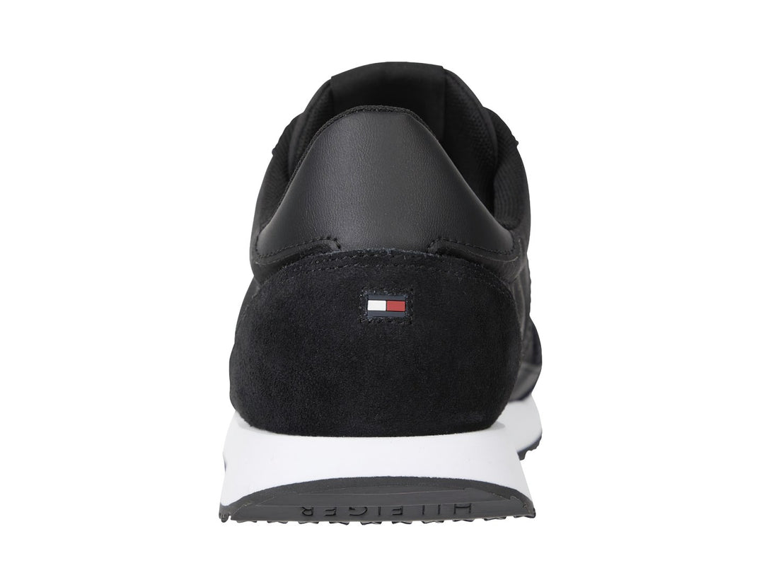 Tenis Tommy Hilfiger negros con suela blanca y detalle de franja roja, blanca y azul en el costado.
