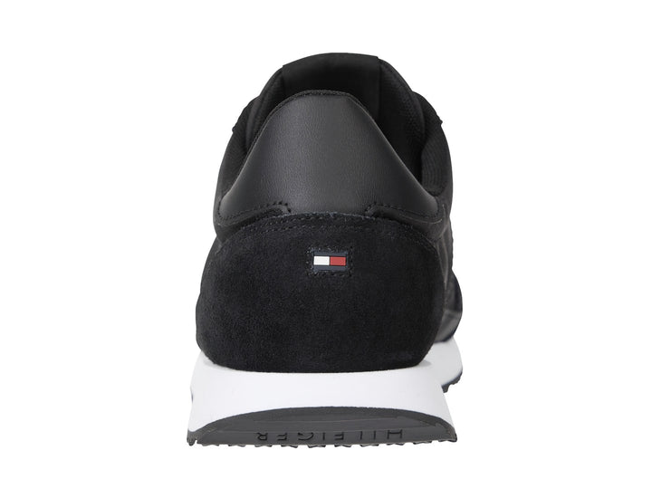 Tenis Tommy Hilfiger negros con suela blanca y detalle de franja roja, blanca y azul en el costado.