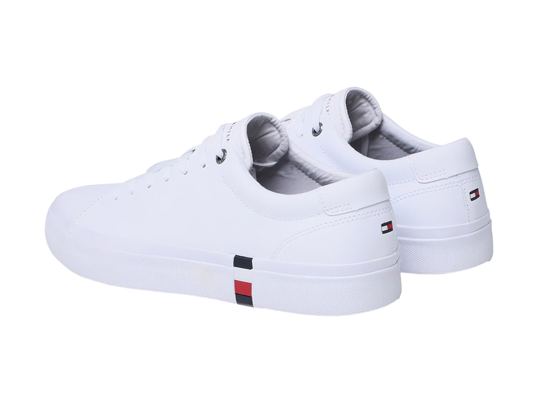 Tenis Tommy Hilfiger color blanco de cuero con detalle tricolor en la suela y agujetas blancas.