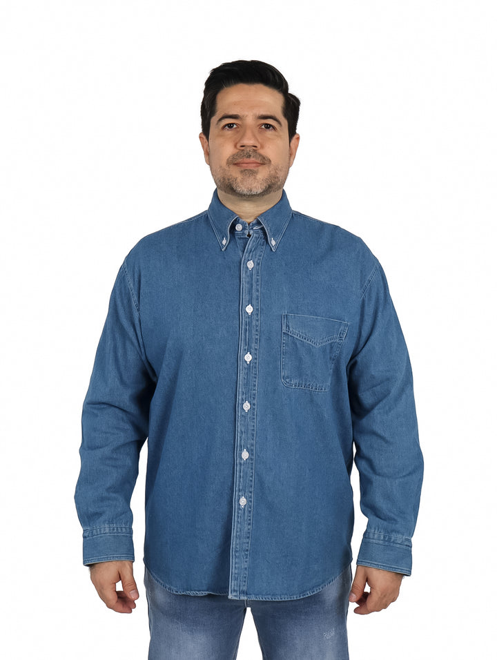 Hombre vistiendo una camisa de mezclilla azul de manga larga con botones blancos y un bolsillo frontal.