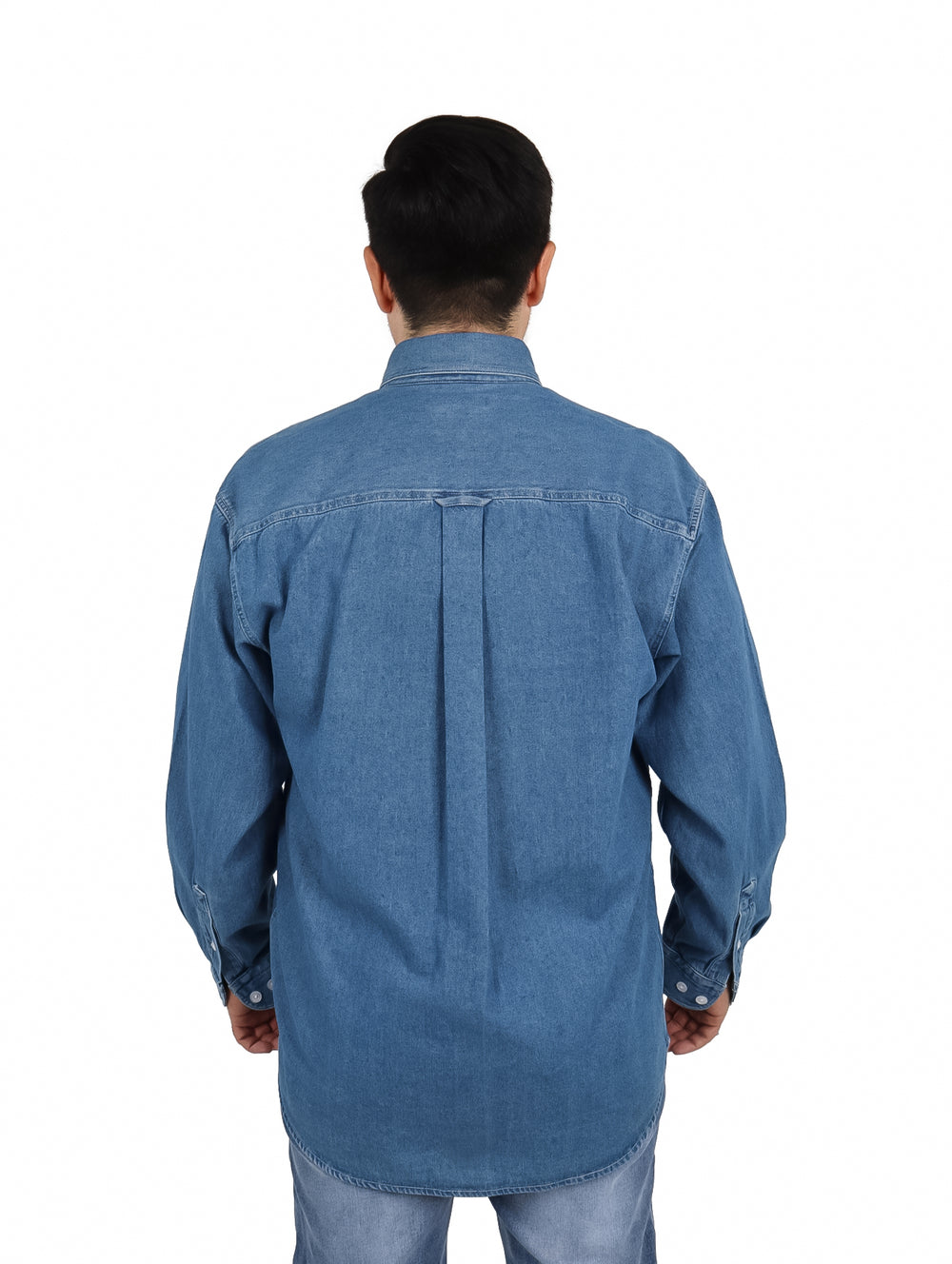 Hombre vistiendo una camisa de mezclilla azul de manga larga con botones blancos y un bolsillo frontal.