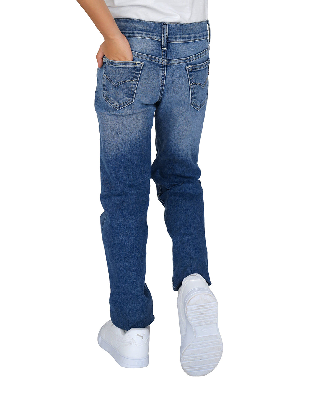 Pantalones vaqueros para niño en color azul stonewash con corte ajustado y calzado blanco.