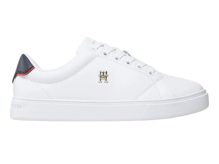 Tenis blancos Tommy Hilfiger de corte bajo con detalle azul y rojo en el talón y logo dorado lateral.