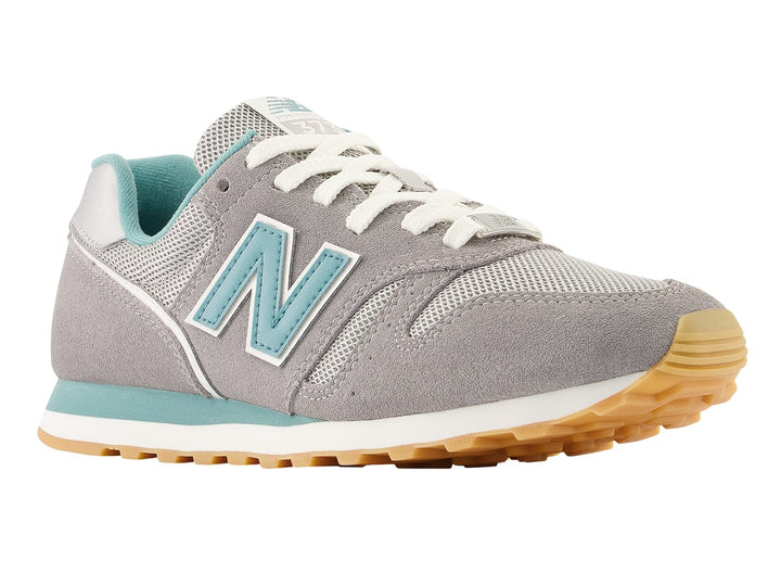 Tenis New Balance color gris con detalles en azul turquesa y suela color miel.