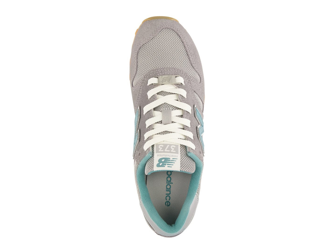 Tenis New Balance color gris con detalles en azul turquesa y suela color miel.